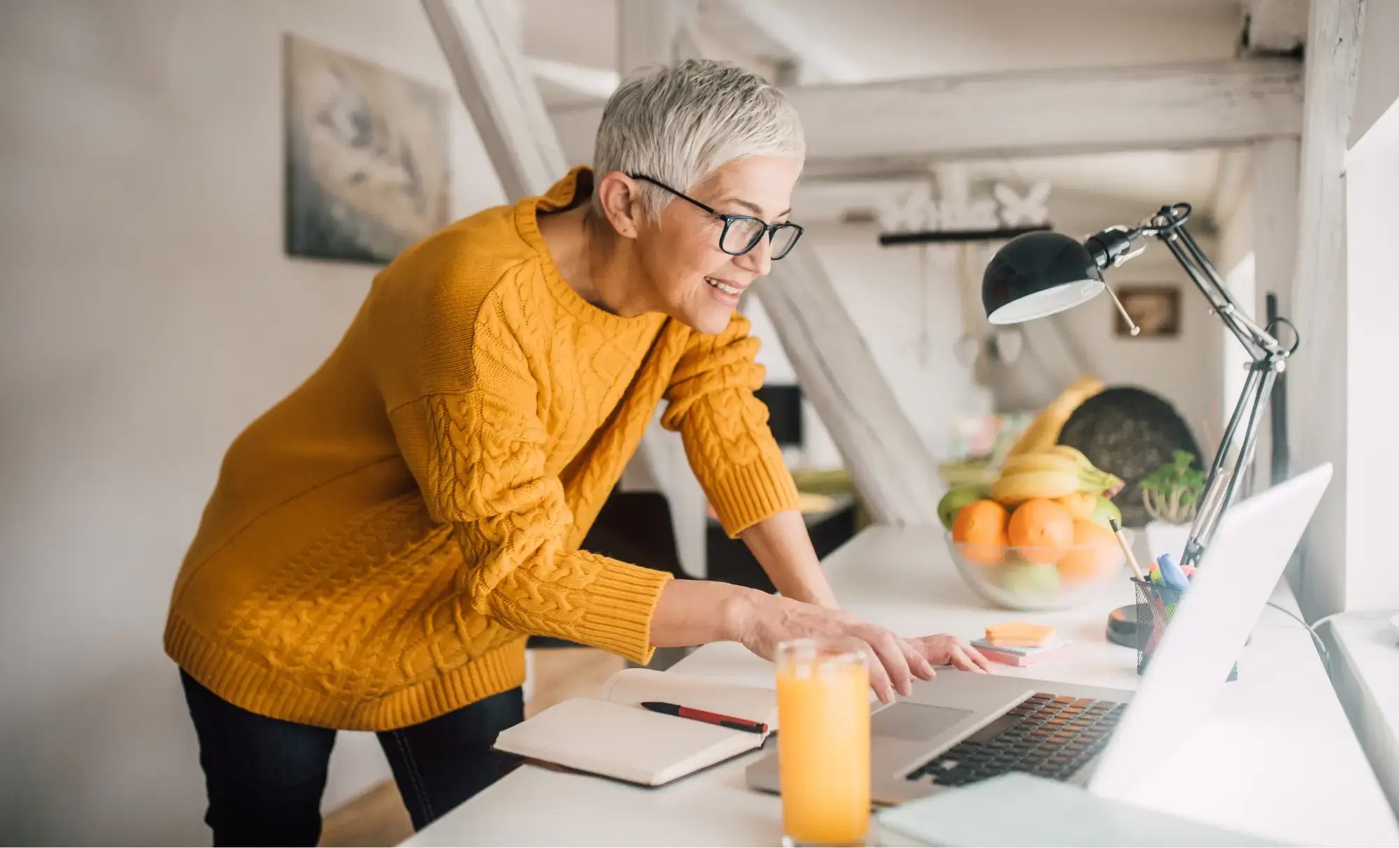 Kvinnlig konsult står upp och tittar på datorn på sitt vita skrivbord. Upptäcker acconomy, Sveriges enklaste bokföringssystem
